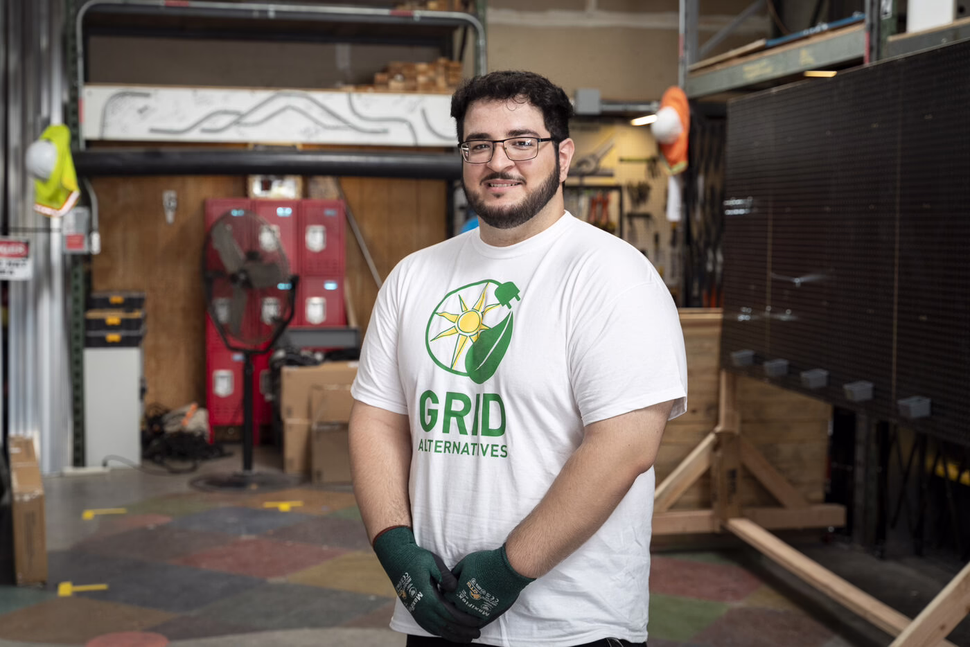 A young man in a solar-installation training program smiles in a workshop.