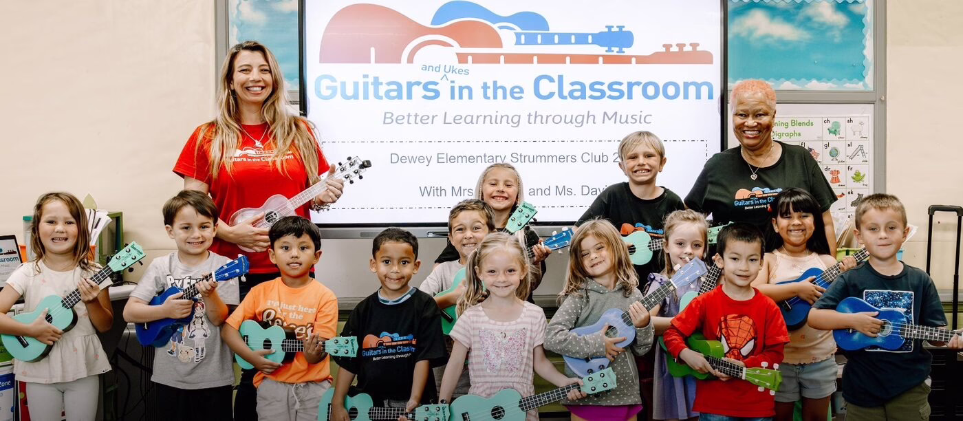Students play guitars together in a classroom.